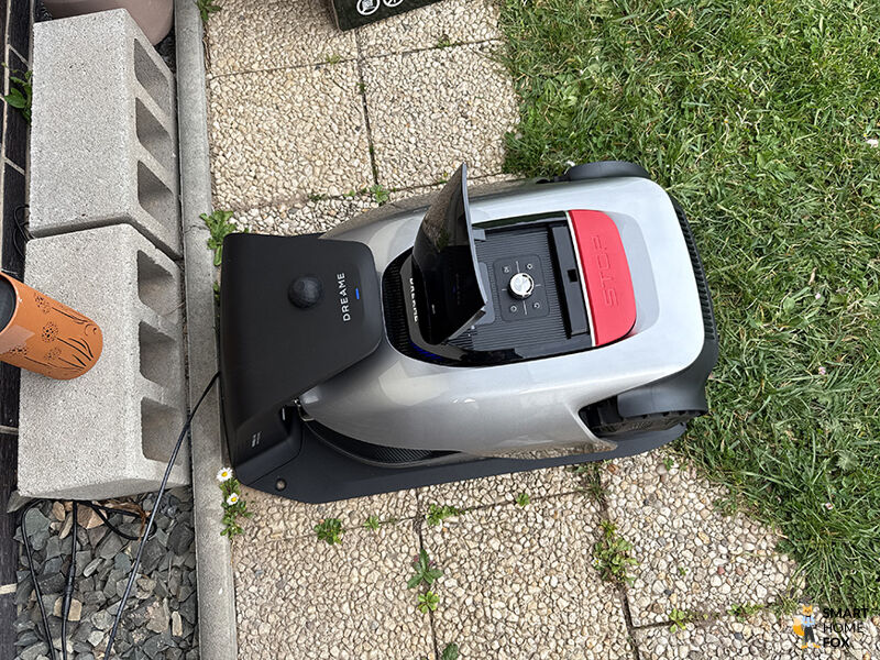 Der Dreame A2 Mähroboter steht sauber geparkt in seiner Ladestation im Garten.